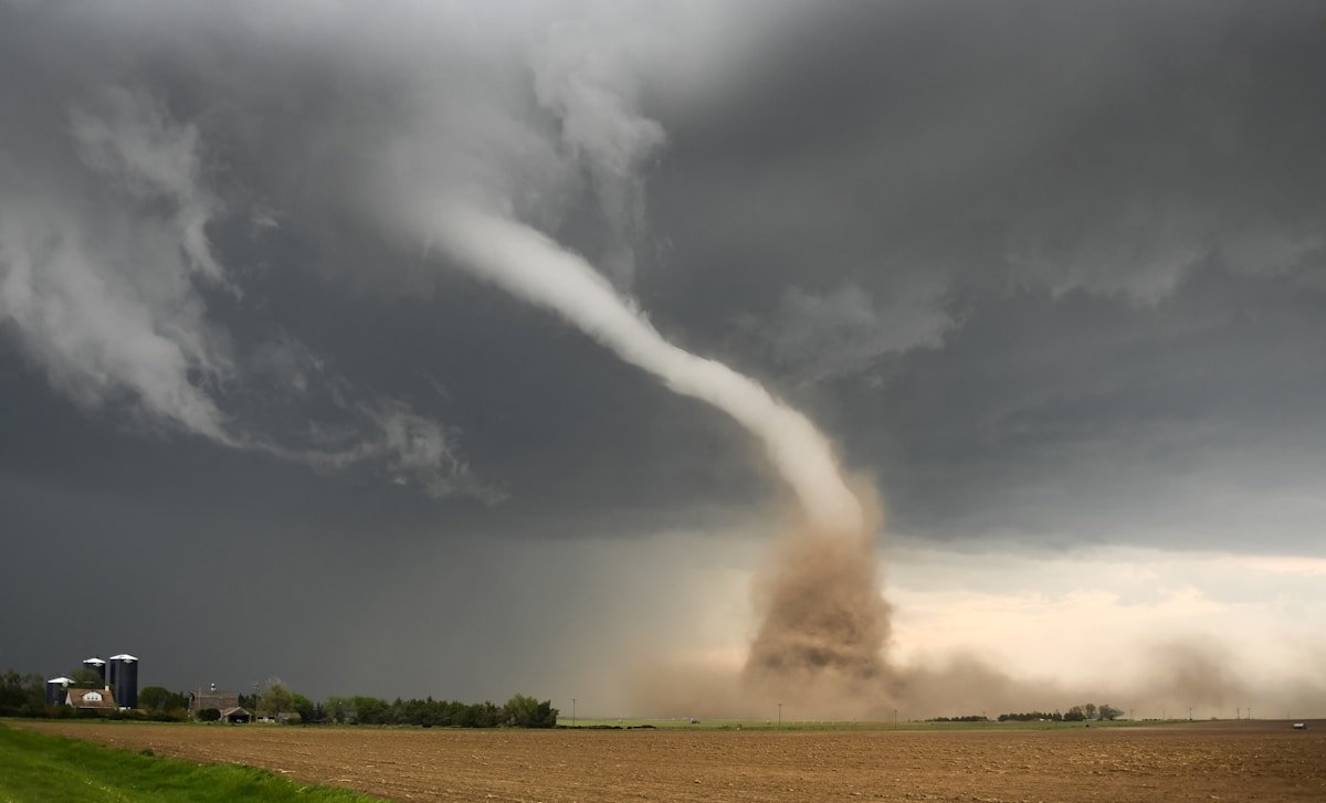 Dusty tornado crossing the US plains with dark storm clouds overhead