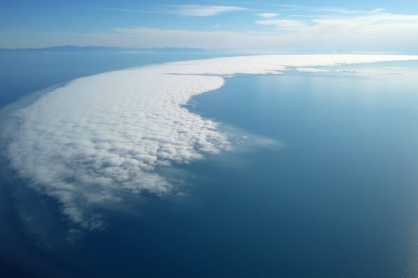 Satellite view of an atmospheric river moisture band, a narrow concentrated plume of water vapor stretching across the Pacific Ocean approaching the California coast. Atmospheric rivers explained: invisible sky rivers carrying more water than the Amazon.