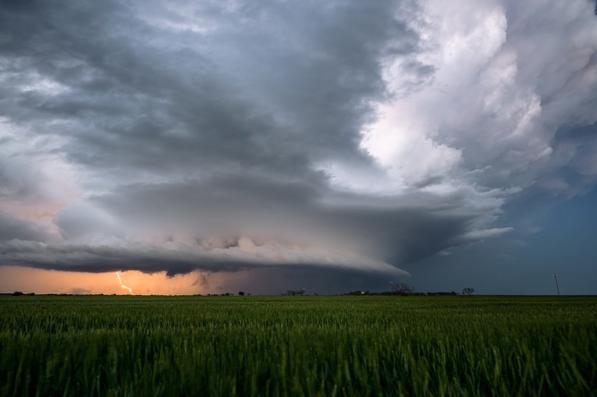 Storm approaching over a green field, dramatic sky and hurricane weather