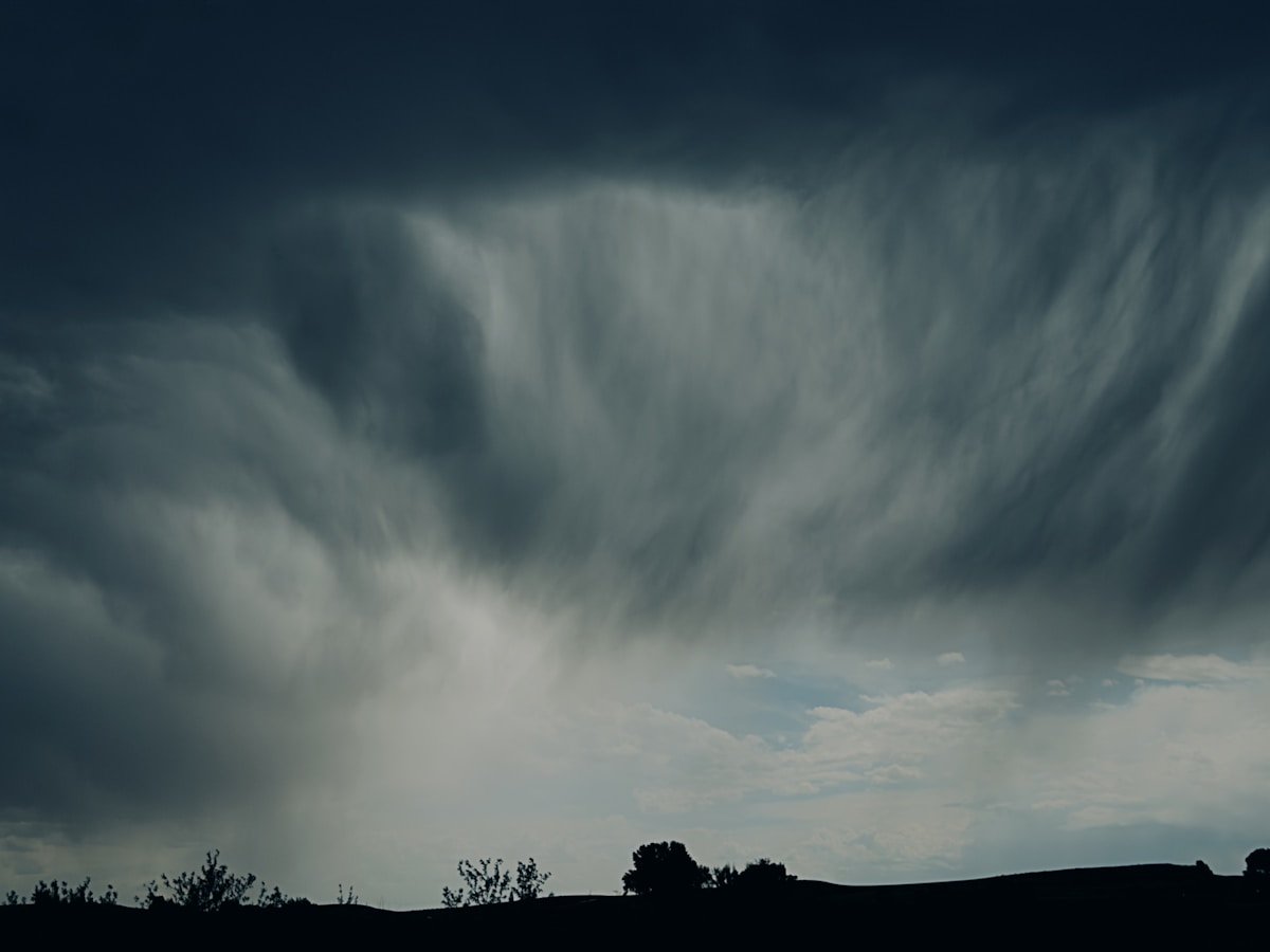 Dark dramatic storm clouds gathering over silhouetted horizon