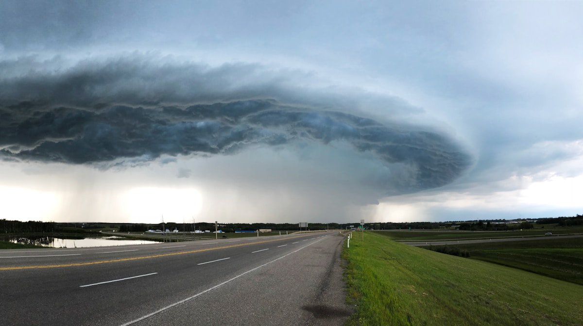 A tornado visible over a rural road with dramatic storm clouds