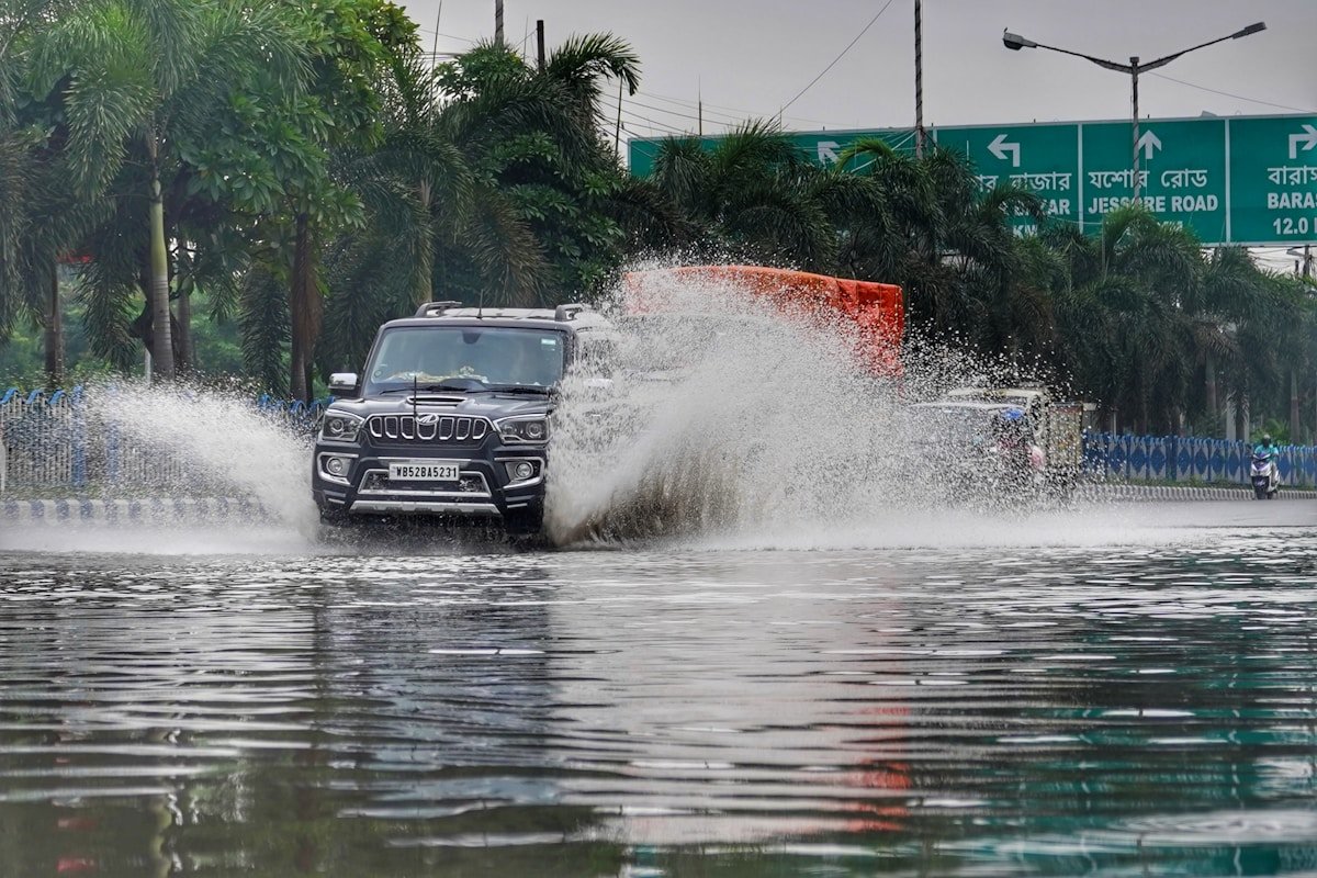 Flooded street during heavy monsoon rainfall with a vehicle navigating through water