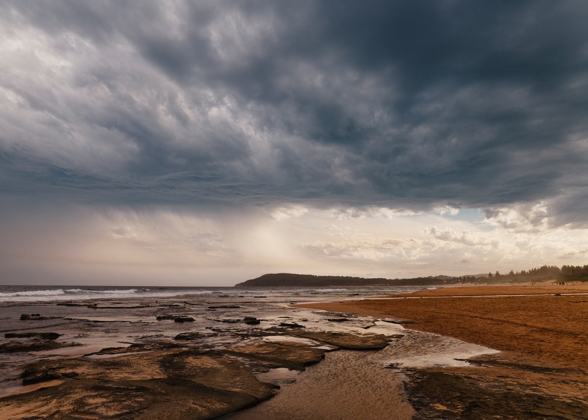 Dramatic storm clouds gathering over a rocky coastline before a storm
