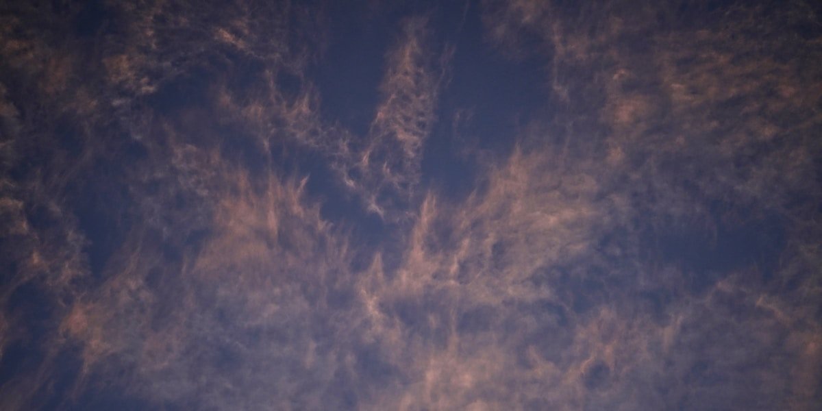 Wispy clouds streaking across a dark blue sky