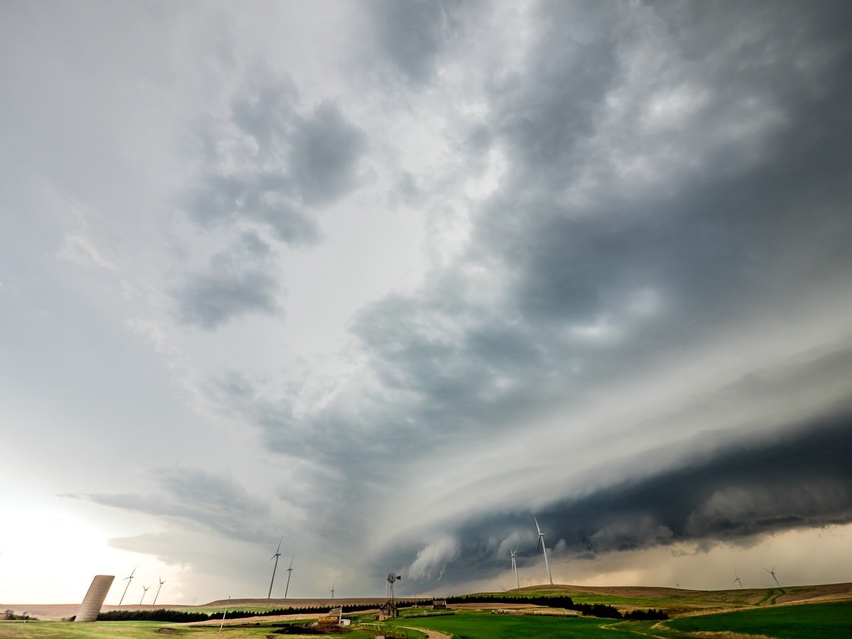 Tornado touching down in open field under dark storm clouds