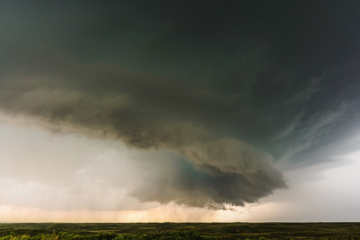 Storm clouds forming over a field at sunset