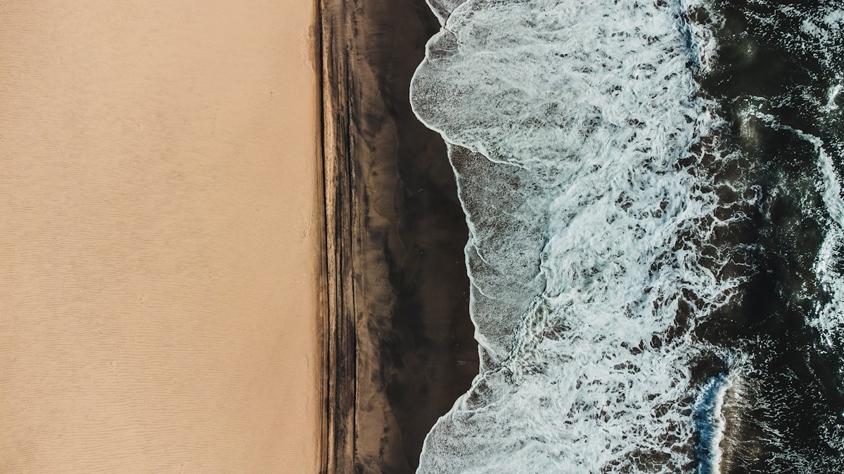 Ocean waves crashing on a sandy beach from above