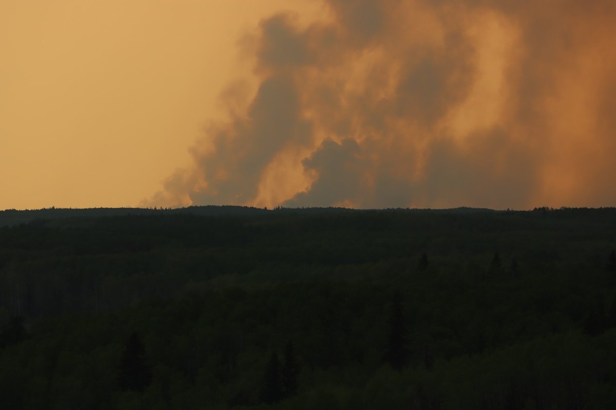 Large plume of smoke rising from a forest fire in Alberta