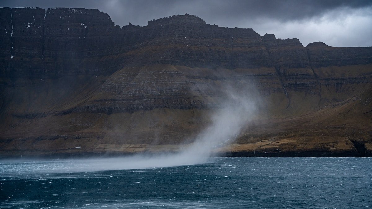 Waterspout swirling across the sea near mountains