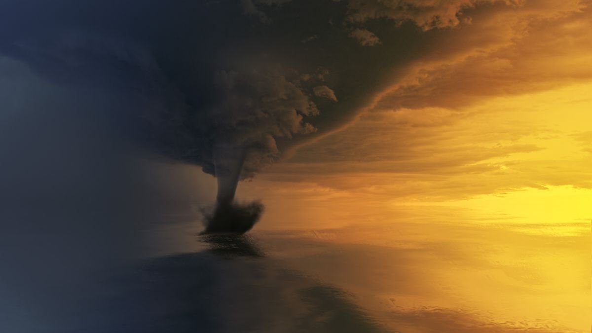 Massive supercell thunderstorm with rotating wall cloud and tornado funnel descending over open plains at twilight